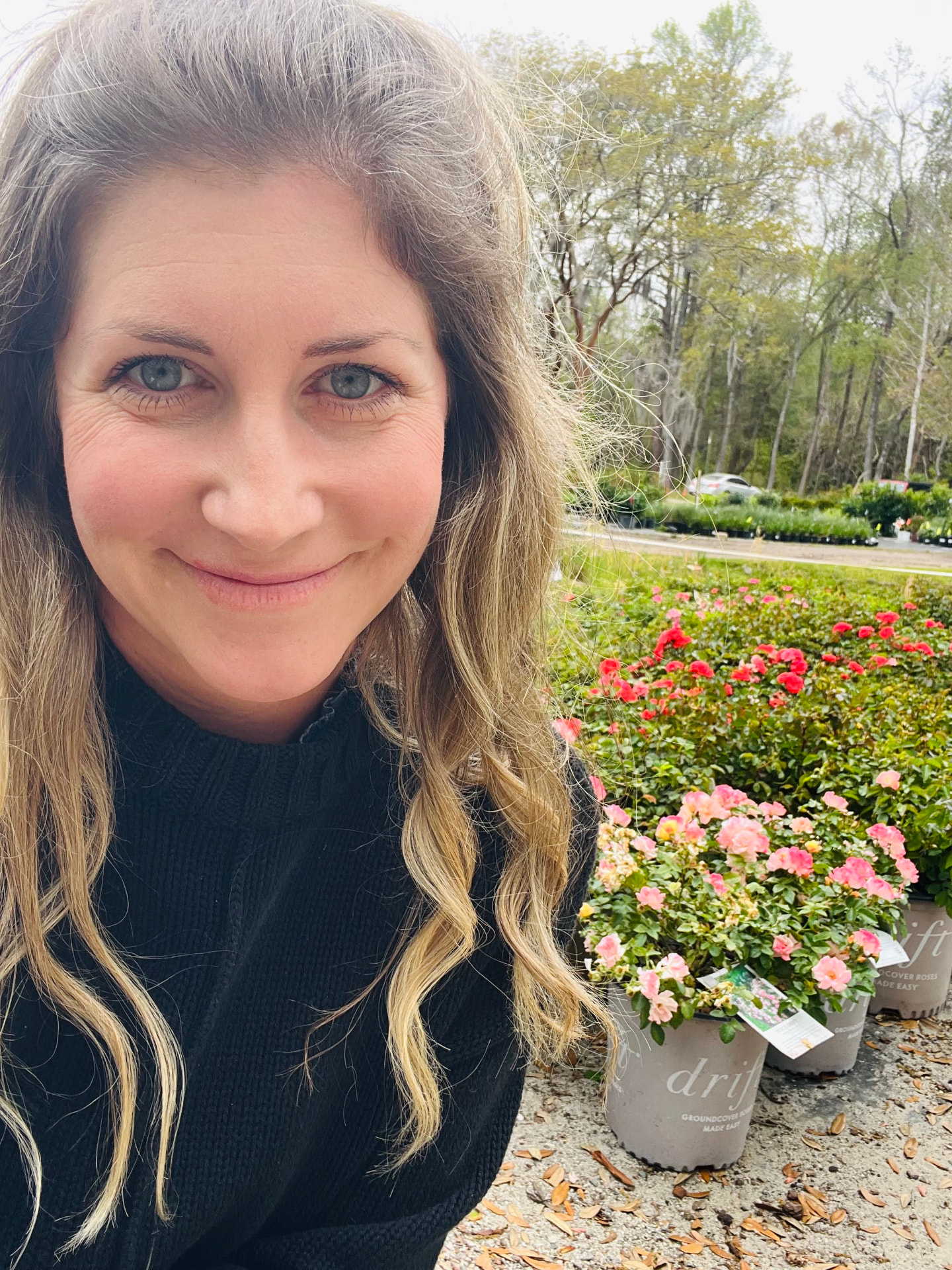 Claire, owner of Lowcountry in Bloom, among rose bushes at a plant nursery