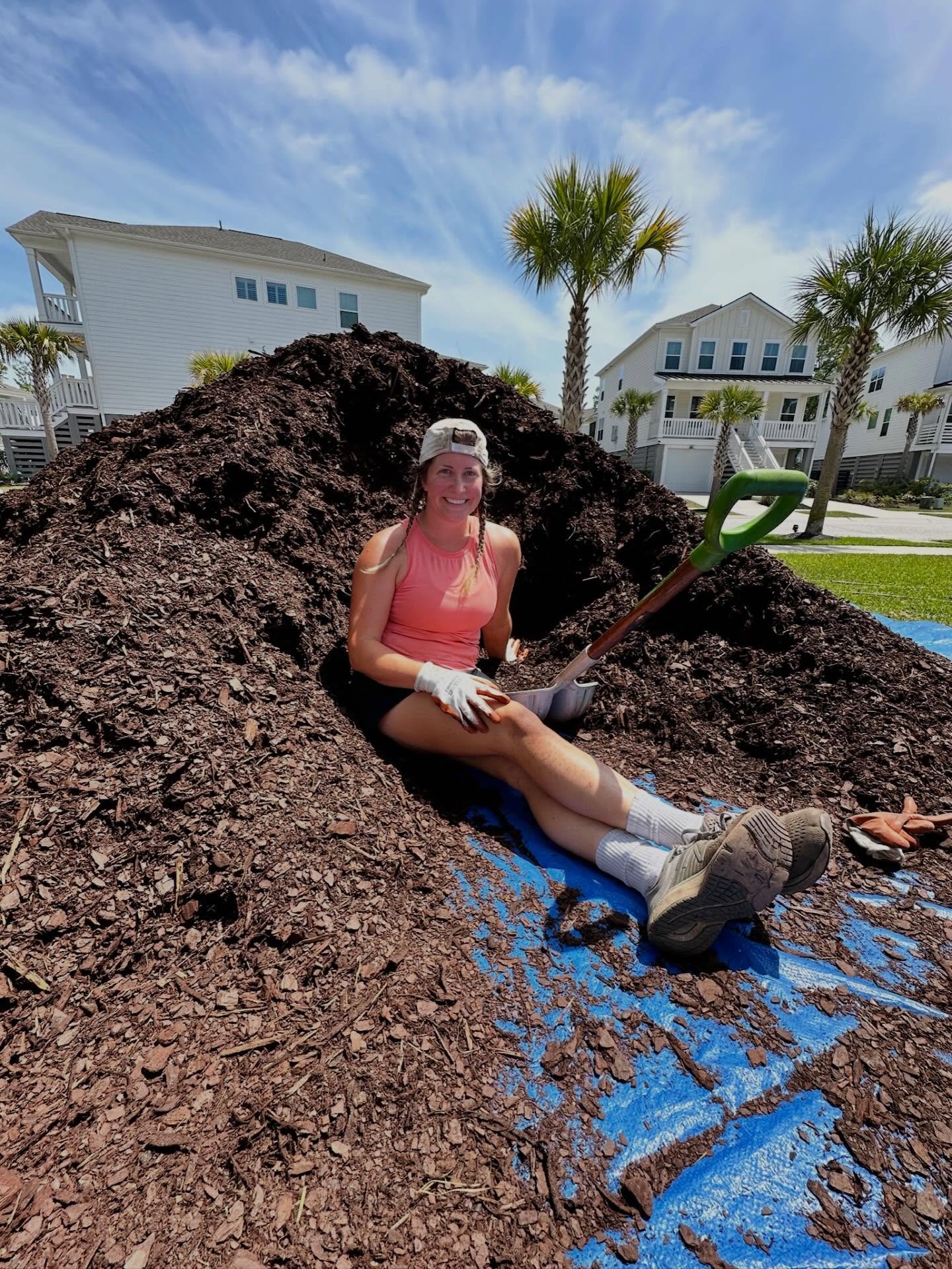 Claire, owner of Lowcountry in Bloom, on a job site with a pile of mulch